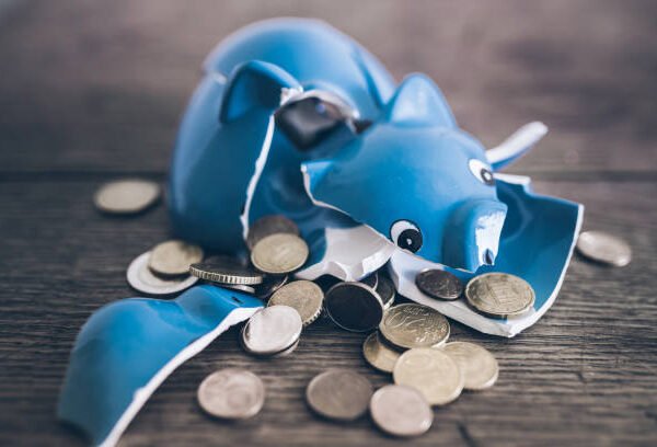 closeup of shattered broken piggy bank with coins on rustic wooden table closeup of shattered broken piggy bank with coins on rustic wooden table
